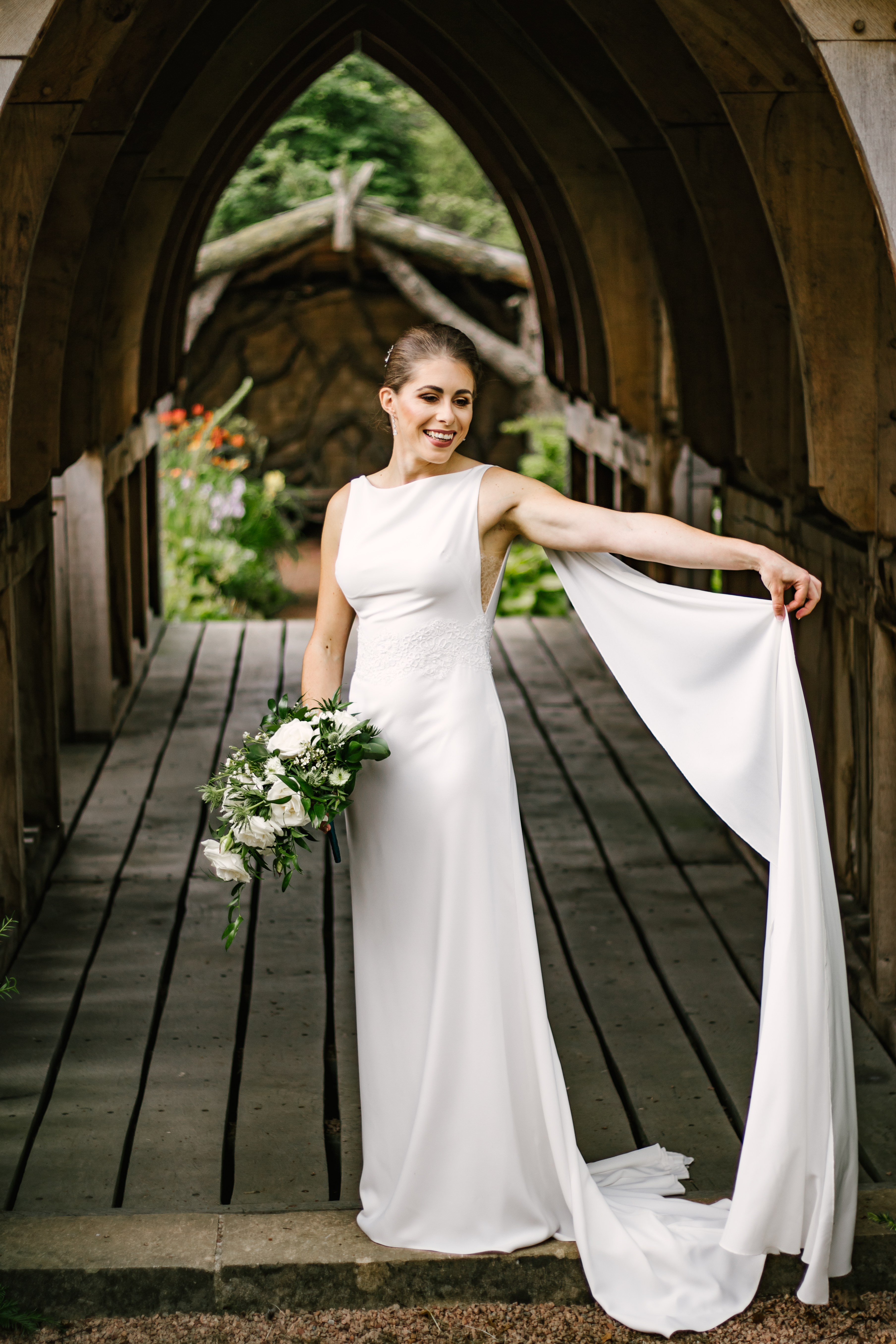 Anna & David — bride holding her bouquet beneath a wooden gothic arch